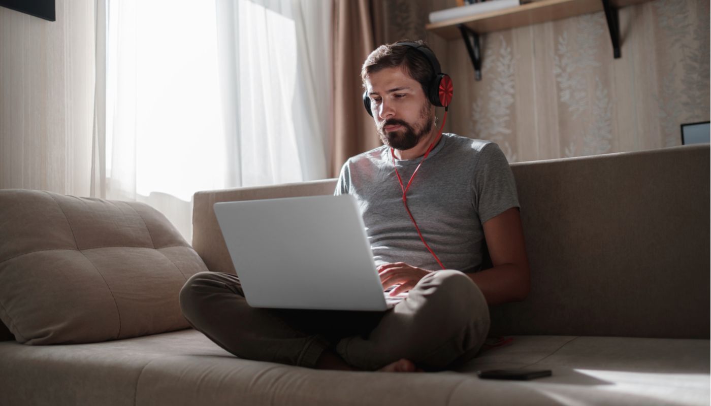 Man sitting cross legged on couch with laptop.  